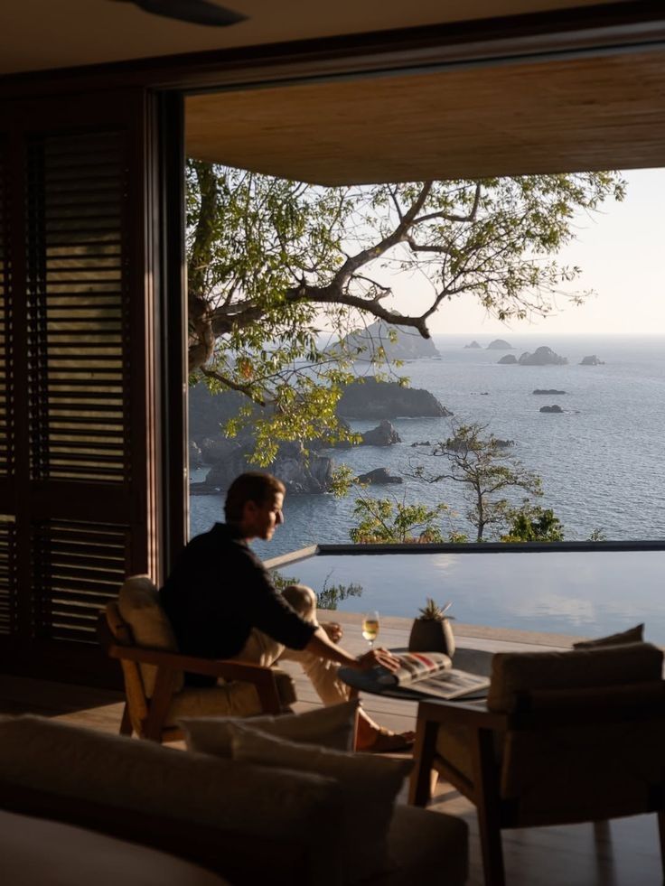 An interior at dusk, ocean visible through tall windows